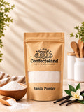 A kraft paper stand-up pouch labeled Confectoland Vanilla Powder, styled on a tabletop with vanilla beans, a flower, a small bowl of vanilla powder, and wooden utensils in the background.